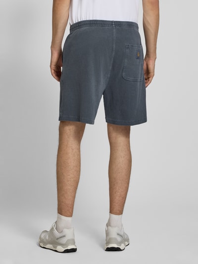 Männermodel trägt Regular Fit Shorts mit elastischem Bund Modell 'Harper' von Carhartt Work In Progress in Blau, gewachste Baumwolle, Ganzkörperansicht Rückansicht.