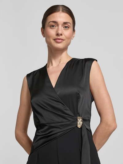 Vrouwenmodel draagt Regular Fit Jumpsuit mit Zierbesatz van Rinascimento in zwart satijn met V-hals, mouwloos, taillering, sierbeslag, detailopname bovenlichaam.