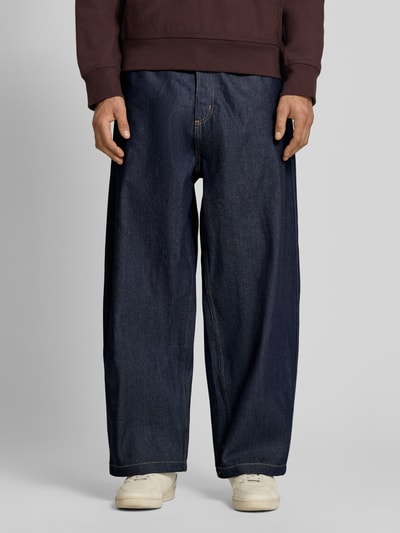 Männermodel trägt Relaxed Fit Jeans mit Eingrifftaschen Modell 'Brandon' von Carhartt Work In Progress im dunklen Blau, Material-Mix, Nahaufnahme Unterkörper. Kontext: Herren Jeans, Relaxed-Fit, Bundweite 45 cm, Innenbeinlänge 70 cm, Größe M.