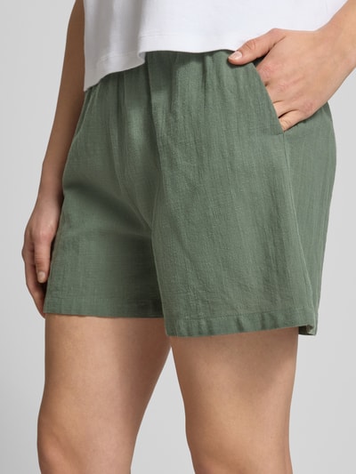 Vrouwenmodel draagt Regular Fit bermudashorts uit puur katoen model 'TIZANA' van Only in effen groen met gevlamd garen, zijsteekzakken, tunnelkoord in elastische boord, detailopname dijbeen.