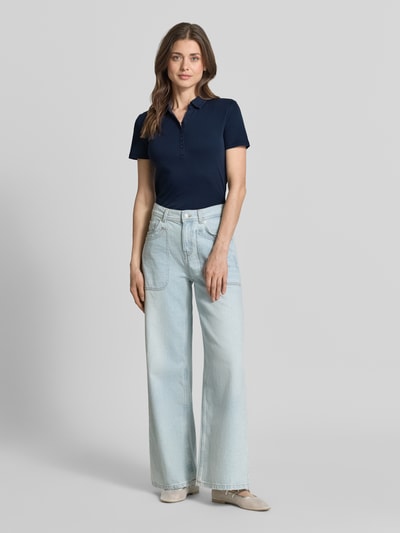 Modelka nosi Regular Fit Poloshirt aus reiner Baumwolle von Tom Tailor, kolor jednolity, krój regular fit, polokrag, dekolt w szpic, krótka listwa guzikowa, krótki rękaw, dzianina, bawełna, widok całej sylwetki od frontu