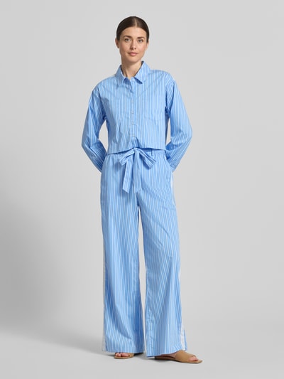 Frauenmodel trägt Wide Leg Pants mit Bindegürtel Modell 'Dana' von GUIDO MARIA KRETSCHMER WOMAN, hellblau-weiß gestreift, Ganzkörperansicht von vorne, Baumwoll-Mix mit Stretch-Anteil, ausgestellter Schnitt, französische Eingrifftaschen, Gesäßtaschen, elastischer Bund.
