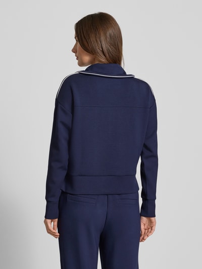 Frauenmodel trägt Sweatshirt mit kurzem Reißverschluss von Christian Berg Woman in Dunkelblau, Material-Mix mit Modal-Anteil, Lockerer-Schnitt, Umlegekragen, gerippte-Abschlüsse, Ganzkörperansicht Rückansicht.