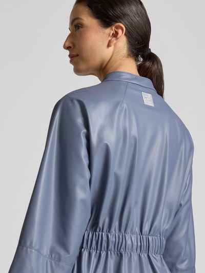 Frauenmodel trägt Blazer in Leder-Optik mit Stehkragen von Marc Cain in Blau, tailliert, glatte Oberfläche, Rückansicht, Nahaufnahme Oberkörper. Rückenlänge 54 cm, Brustweite 48 cm, Ärmellänge 49 cm, 3/4-Arm, Reißverschluss.