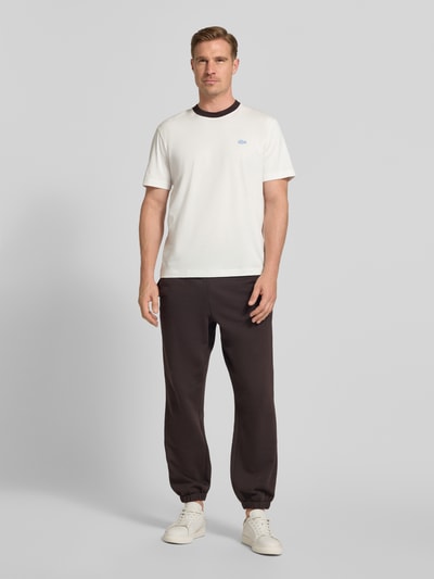 Männermodel trägt Regular Fit T-Shirt aus reiner Baumwolle von Lacoste, Optik: Unifarben, Logo-Detail, Rundhals, Kurzarm, Jersey, Ganzkörperansicht von vorne.