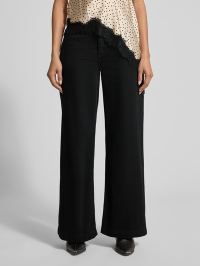 Frauenmodel trägt Wide Leg Jeans mit Eingrifftaschen Modell 'LIA' von Mango, schwarze Baumwolle, Nahaufnahme Oberkörper bis Füße.
