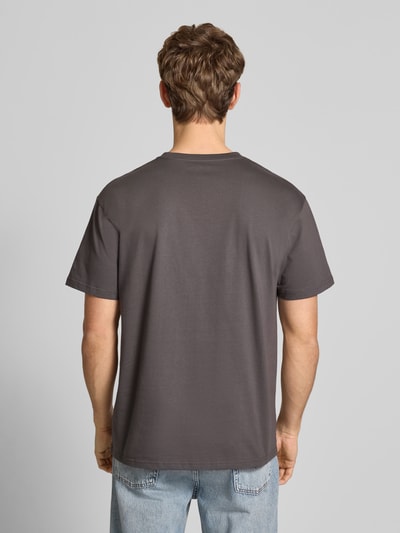 Männermodel trägt T-Shirt mit Label-Stitching Modell 'CHASE' von Carhartt, reine Baumwolle, Regular Fit, Rückenansicht, Ganzkörperansicht.