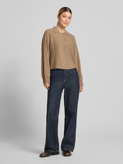 Frauenmodel trägt beigefarbene Regular Fit Strickjacke aus reiner Wolle Modell 'Dulena' von OPUS zu weiter Jeans, Ganzkörperansicht von vorne. Damen Pullover von OPUS.