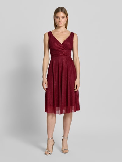 Kobiece model nosi Knielanges Cocktailkleid mit V-Ausschnitt od TROYDEN COLLECTION z szyfonu, taliowany, długość do kolan, dekolt w serek, szerokie ramiączka, dekolt na plecach, zamek błyskawiczny z tyłu, długość tyłu w rozmiarze 36: 85 cm, szerokość w rozmiarze 36: 43 cm, kolor bordowy, delikatna tekstura, gładka powierzchnia, widok całej sylwetki z przodu.
