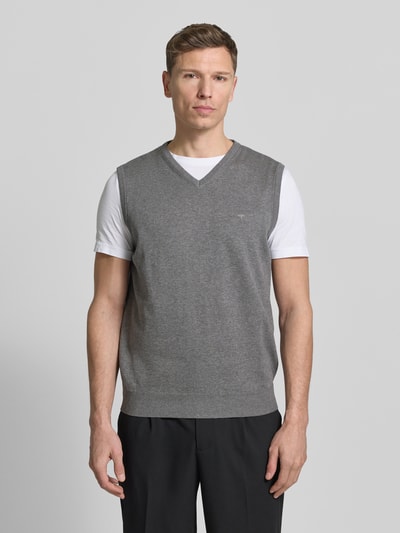 Männermodel trägt grauen Pullunder mit Label-Stitching von Fynch-Hatton aus reiner Baumwolle, Regular-Fit, V-Ausschnitt, Gerippte-Abschlüsse, Ganzkörperansicht von vorne.