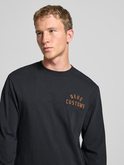 Männermodel draagt Regular Fit Shirt met lange mouwen met logostitching Model 'Engineer' van DEUS EX MACHINA, puur katoen, ronde hals, zwarte stof, ruglengte maat M 70 cm, Nahaufnahme Oberkörper.