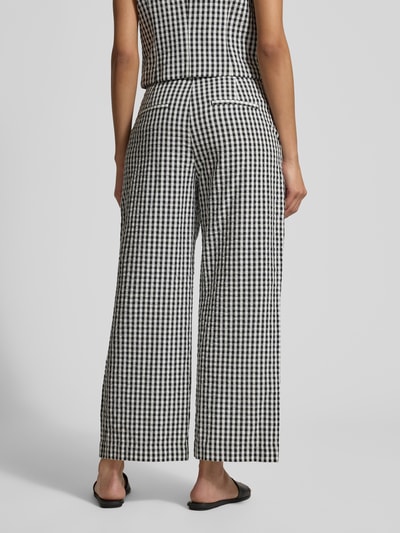 Modelka nosi Hose im Allover-Look von Jake*s Casual, czarno-biała krata, proste nogawki, kieszenie, szerokość w rozmiarze 38: 40 cm, długość wewnętrzna nogawki: 68 cm, pełny widok sylwetki od tyłu.
