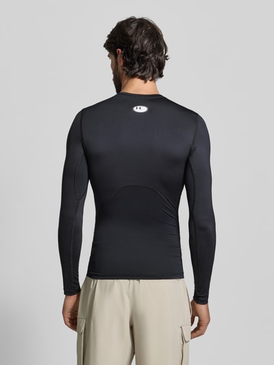 Männermodel trägt schwarzen Slim Fit Longsleeve mit Logo-Print von Under Armour, elastischer Material-Mix, Rundhalsausschnitt, Ganzkörperansicht Rückansicht.