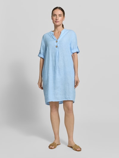 Frauenmodel trägt Tunikakleid aus Leinen mit V-Ausschnitt Modell 'Ki44ra' von ZABAIONE in Hellblau, Knopfleiste, Ärmel mit Aufschlag, Gerader-Schnitt, Rückenlänge 95 cm, Brustweite 50 cm, Ärmellänge 26 cm, Ganzkörperansicht von vorne.