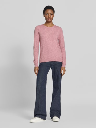 Frauenmodel trägt Strickpullover aus Viskose-Mix von VILA in Rosa, gerippter Rundhalsausschnitt, taillierte Passform, Ganzkörperansicht von vorne.