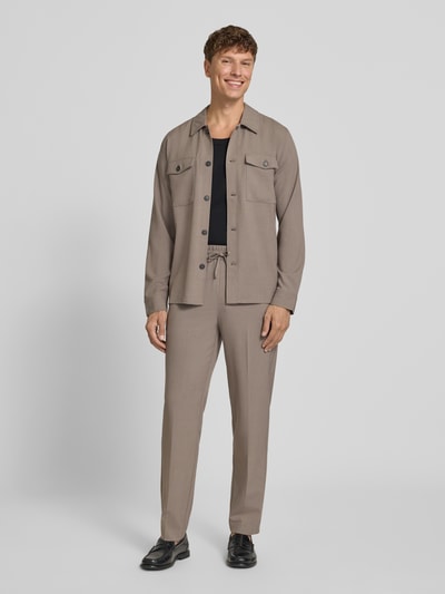 Männermodel trägt Relaxed Fit Hemdjacke mit Brusttaschen von Lindbergh, Material-Mix mit Viskose-Anteil, Kentkragen, Knopfleiste, Herren, Rückenlänge 73 cm, Größe M, sandfarbener Stoff, strukturierte Optik, Ganzkörperansicht von vorne.