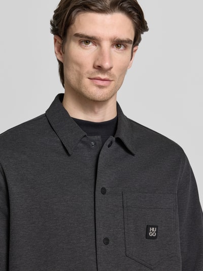Männermodel trägt Oversized Hemdjacke aus Baumwoll-Mix Modell 'ENASO' von HUGO, unifarben, Melange, Label Patch, Nahaufnahme Oberkörper.