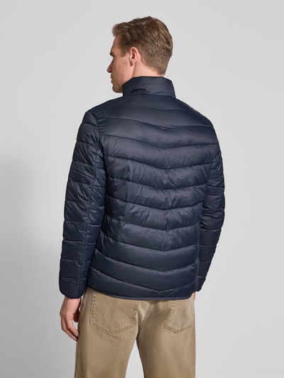 Männermodel trägt Regular Fit Steppjacke mit vertikaler Reißverschlussbrusttasche von Tom Tailor Denim, Optik: Unifarben, Ganzkörperansicht Rückansicht.