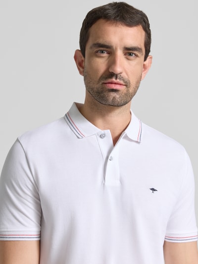 Männermodel trägt Regular Fit Poloshirt mit Label-Stitching von Fynch-Hatton aus reiner Baumwolle in Weiß, Nahaufnahme Oberkörper.