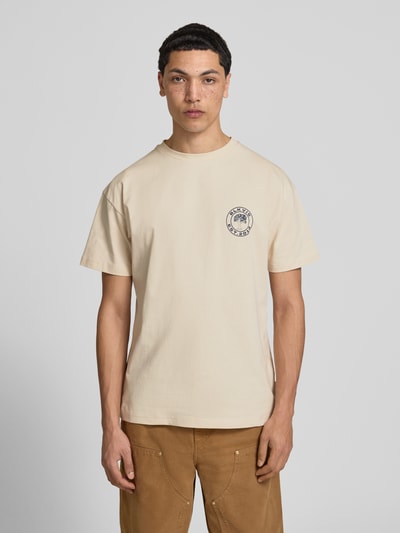 Mannelijk model draagt T-Shirt met Logo und Rundhalsausschnitt van BLKVIS in beige, regular fit, puur katoen, logo op borst, totale lichaamsvoorzijde. Ruglengte maat M: 70 cm.