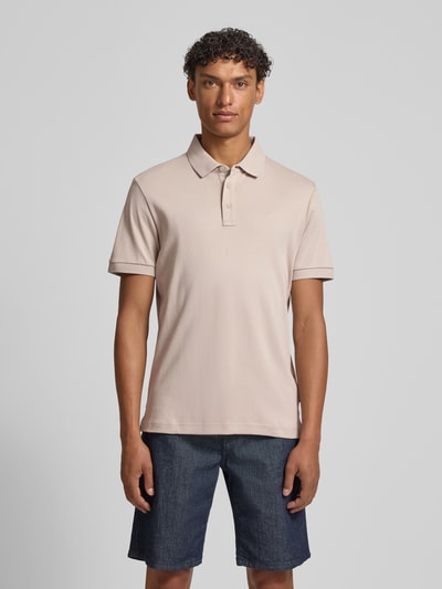 Männermodel trägt Modern Fit Poloshirt mit Logo-Stitching Modell 'Primo' von JOOP! Collection in Beige, Struktur Baumwolle, Ganzkörperansicht von vorne.