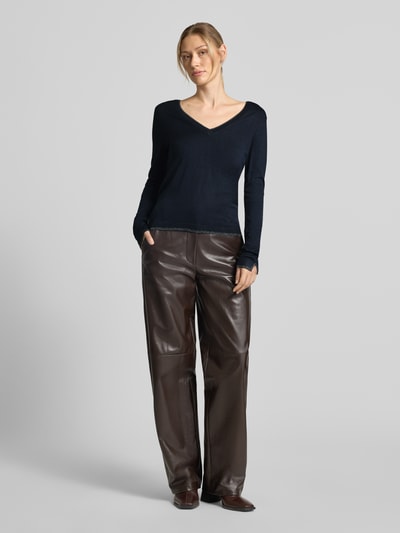 Frauenmodel trägt Slim Fit Longsleeve aus reine Viskose Modell 'Maglia Chiusa' von Liu Jo White in Schwarz, glatte Struktur, V-Ausschnitt, Logo-Detail, kombiniert mit brauner Hose, Damen Longsleeve, Ganzkörperansicht von vorne.