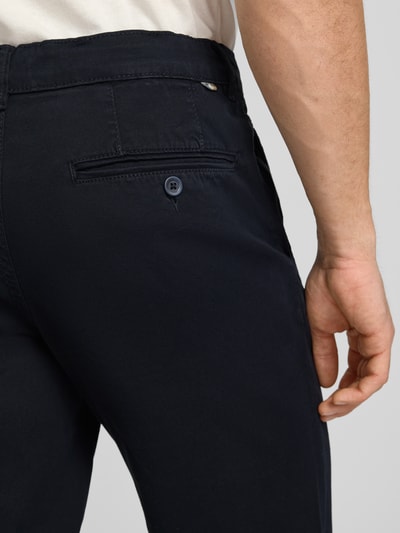 Mężczyznamodel nosi Straight Fit Chino z wpuszczanymi kieszeniami model 'Vance' od Jack & Jones, elastyczna mieszanka bawełny, ciemny kolor, długość wewnętrzna nogawki 67 cm, szerokość w rozmiarze 32/32: 43 cm, zapięcie na guzik i zamek błyskawiczny, widoczna kieszeń z tyłu, detalowa perspektywa tyłu.
