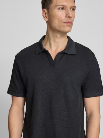 Męski model nosi Comfort Fit Poloshirt mit V-Ausschnitt od Lindbergh z bawełny, fakturowany wzór, detal z logo, długość tyłu 68 cm, rozmiar M, kolor ciemny, półzbliżenie przodu
