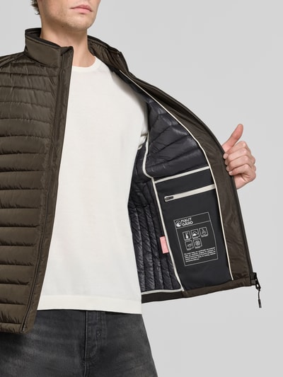 Männermodel trägt Regular Fit Jacke in Stepp-Optik Modell 'OLYMPUS' von NAUTGÅRD, oliv, schwarze Steppstruktur, Nahaufnahme Oberkörper.