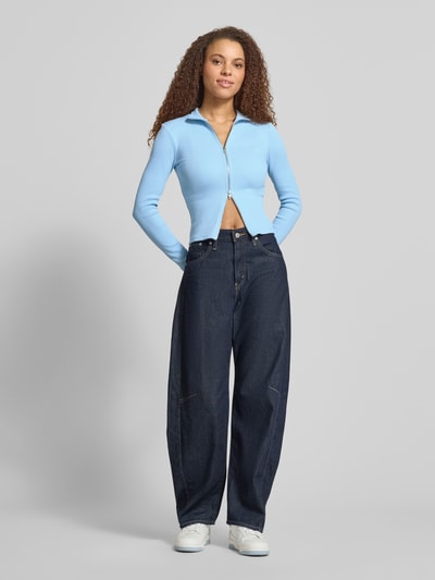 Frauenmodel trägt Slim Fit Jacke mit Stehkragen von Gina Tricot in Hellblau aus elastischem Baumwoll-Mix, Zweiwege-Reißverschluss, Ganzkörperansicht von vorne.