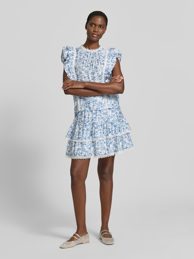 Frauenmodel trägt Ausgestellter Rock aus Viskose-Mix Modell 'BLISS' von Vero Moda mit Optik:Allover-Muster im floralen Design, Mini-Länge, Bundabschluss: Elastisch, Materialverarbeitung: Popeline, Farbgebung in Hellblau und Weiß, Ganzkörperansicht von vorne.