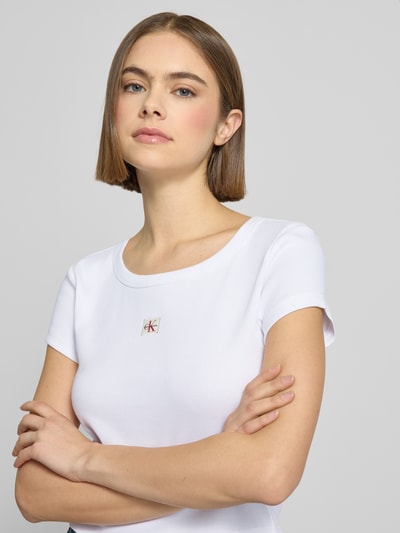 Modelka kobieca nosi Cropped T-Shirt mit Label-Detail od Calvin Klein Jeans, biały, okrągły dekolt, bawełna z elastanem, zbliżenie górnej części ciała.