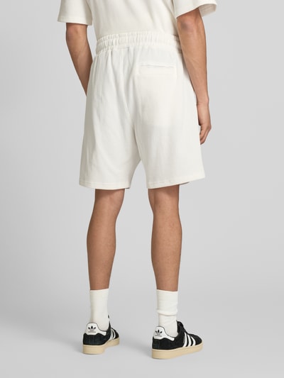 Männermodel trägt Shorts mit Logo-Stitching und elastischem Bund von Pegador aus reine merzerisierte Baumwolle, Loose-Fit, Feinripp, Gesäßtasche, französische Eingrifftaschen, Bundweite 38 cm, Innenbeinlänge 20 cm, Ganzkörperansicht Rückansicht.