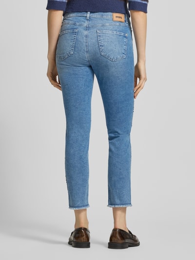 Frauenmodel trägt Slim Fit Jeans aus Baumwoll-Mix Modell 'Ornella' von Angels, hellblau, Galonstreifen aus Pailletten, 7/8-Länge, ausgefranste Beinabschlüsse, 5-Pocket-Design, Ganzkörperansicht Rückansicht.