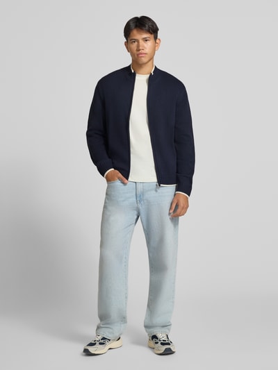 Männermodel trägt Strickjacke mit Reißverschluss Modell 'FREDERIKSBERG' von JACK & JONES, Dunkelblau, Regular Fit, Ganzkörperansicht von vorne. Baumwoll-Mix, gerippter Stehkragen, Kontraststreifen, Rückenlänge 66 cm, Ärmellänge 74 cm.