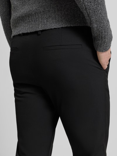 Männermodel trägt Chino mit Eingrifftaschen Modell 'ROBERT' von SELECTED HOMME, Unifarbenes-Design, Material-Mix mit Viskose-Anteil, körpernaher Schnitt, Detailaufnahme Rückansicht.