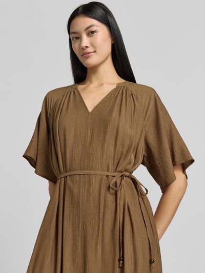 Frauenmodel trägt Relaxed Fit Freizeitkleid aus Viskose-Mix von s.Oliver RED LABEL in Braun mit Bindegürtel, strukturierte Oberfläche, Nahaufnahme Oberkörper.