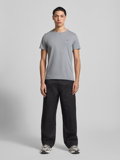 Männermodel trägt Regular Fit T-Shirt aus reiner Baumwolle von Tommy Jeans, Optik: Unifarben, Logo-Stitching, Ganzkörperansicht von vorne.