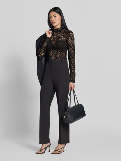 Frauenmodel trägt Slim Fit Longsleeve aus floraler Spitze Modell 'Lacey' von YAS im semitransparenten Design, schwarze Farbe, Ganzkörperansicht von vorne.