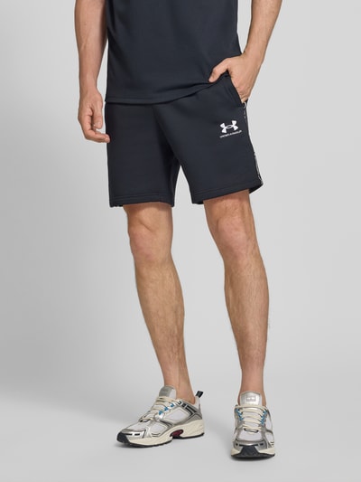 Männermodel trägt schwarze Shorts mit elastischem Bund und Label-Stitching von Under Armour, Baumwoll-Mix, Nahaufnahme Oberkörper.