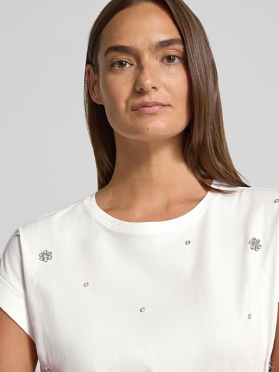 Frauenmodel trägt Damen T-Shirt mit Ziersteinbesatz und Rundhalsausschnitt von Christian Berg Woman in Weiß aus reiner Baumwolle, Regular-Fit, Nahaufnahme Oberkörper.