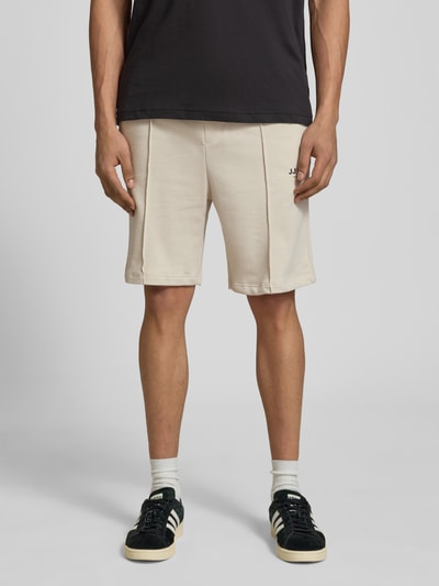 Männermodel trägt Sweatshorts mit Logo Modell 'KANE' von Jack & Jones aus Baumwoll-Mix, Relaxed-Fit, elastischer Bund, helle Farbe, Ganzkörperansicht von vorne. Bundweite 42 cm, Innenbeinlänge 19 cm bei Größe M.