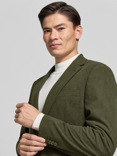 Männermodel trägt Regular Fit Sakko in Cord-Optik von Christian Berg Men in Olivgrün, Feinstruktur, Reverskragen, Nahaufnahme Oberkörper.
