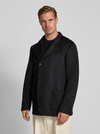 Männermodel trägt Slim Fit Jacke aus Lanawoll-Mix mit Stehkragen von Emporio Armani in Schwarz, aufgesetzte Taschen, Ganzkörperansicht von vorne.