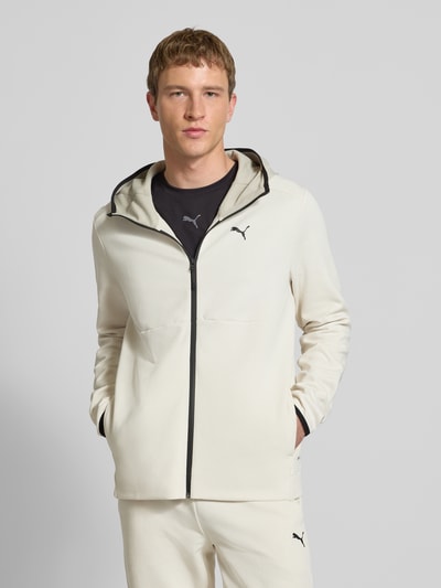 Männermodel trägt Sweatjacke mit Kapuze von PUMA PERFORMANCE in Creme mit schwarzem Reißverschluss, Baumwoll-Mix, Lockerer-Schnitt, Label-Print, Eingrifftaschen, Rückenlänge 69 cm, Ärmellänge 70 cm, Ganzkörperansicht von vorne.