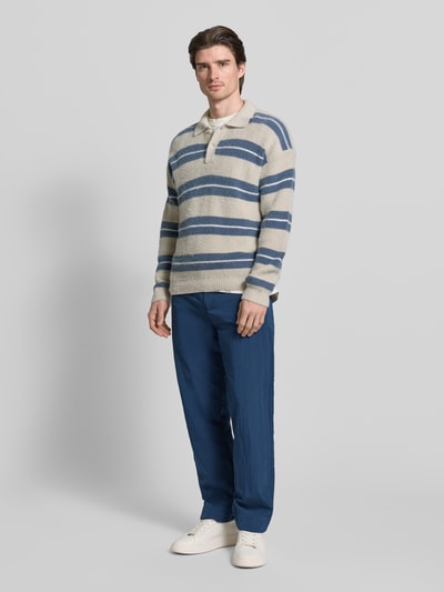 Männermodel trägt Straight Fit Chino mit integriertem Gürtel Modell 'STRAIGHT-7' von BOSS Orange in Unifarbe Blau, Ganzkörperansicht von vorne.
