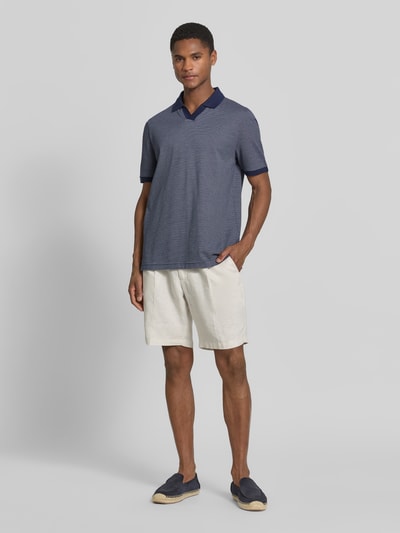 Männermodel trägt Regular Fit Poloshirt aus Baumwolle mit V-Ausschnitt von MAERZ Muenchen in Blau, Ganzkörperansicht von vorne. Rückenlänge bei Größe 50: 71 cm, Label-Detail.