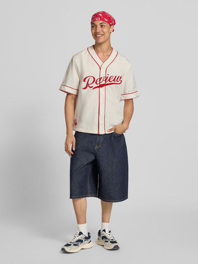 Männermodel trägt Relaxed Fit Freizeithemd mit Logo von REVIEW aus Reine Baumwolle, V-Ausschnitt, rote Details, Ganzkörperansicht von vorne.