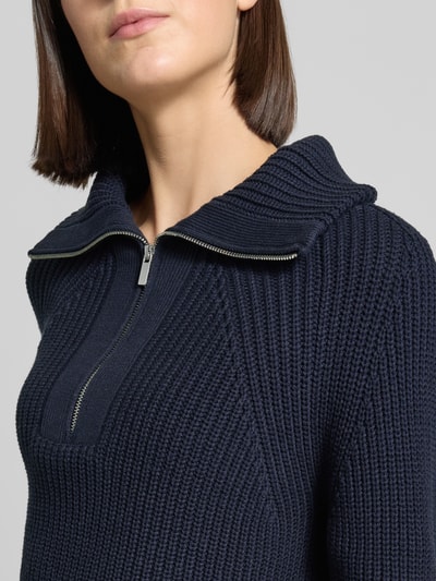 Frauenmodel trägt Regular Fit Troyer aus Baumwoll-Mix von Oui in Dunkelblau, grobe Strickstruktur, silberfarbener Reißverschluss, Nahaufnahme Oberkörper.