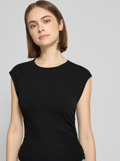Frauenmodel trägt Slim Fit T-Shirt aus Baumwoll-Mix Modell 'MIRA' von Only in Schwarz, unifarben, kurzarm, Nahaufnahme Oberkörper.